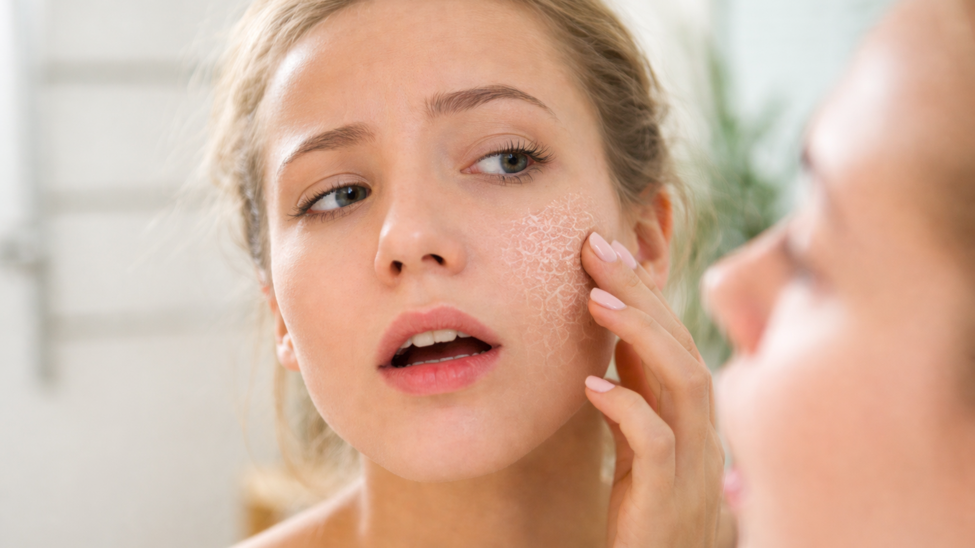 Woman examining dry irritated facial skin in mirror